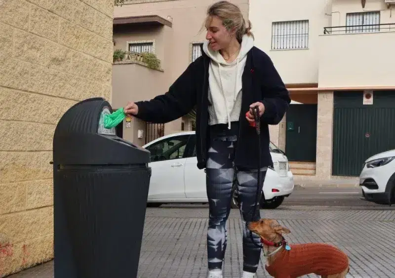 Joven tirando una bolsa con excrementos de su mascota a la papelera / Ayuntamiento de Alcalá